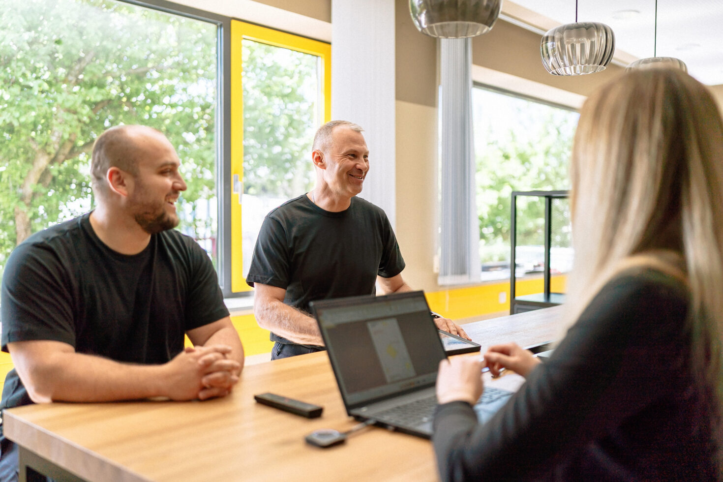 Drei Mitarbeitende an Bespredchungstisch mit Laptop