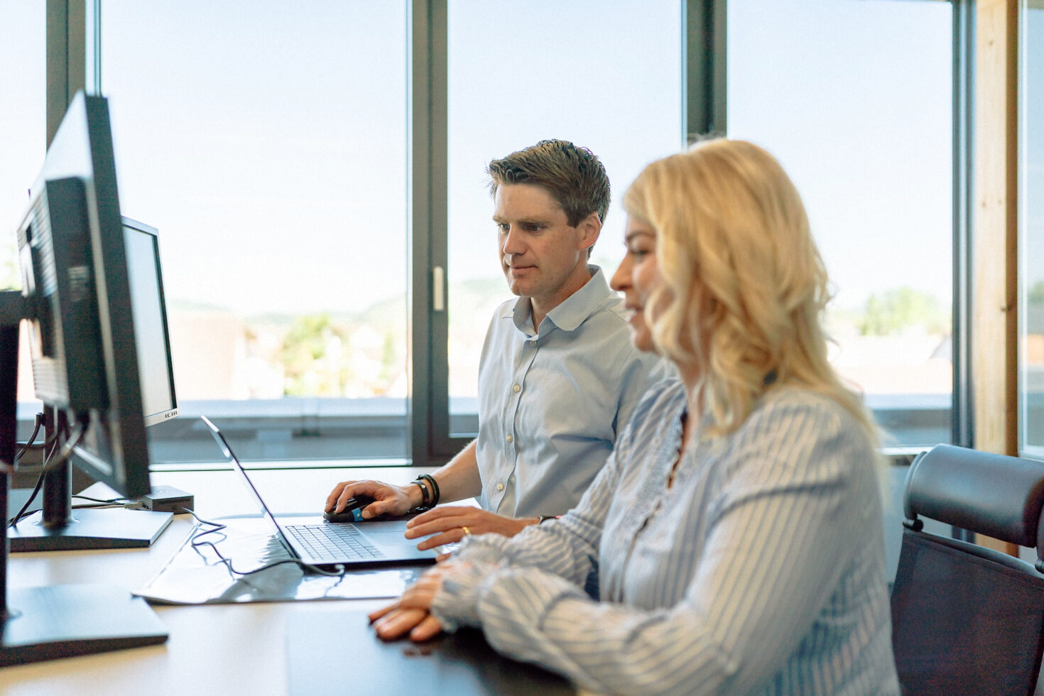 Zwei Mitarbeitende vor dem Computer