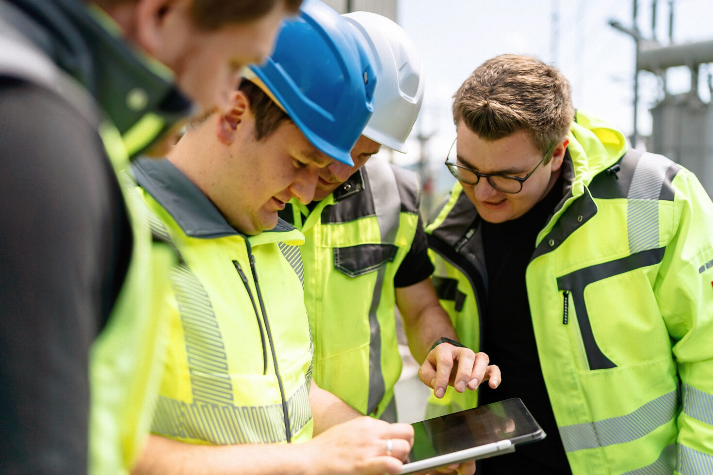 Vier Mitarbeiter in Arbeitskleidung am Tablet